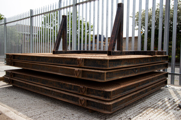 collection of steel mobile crane mats stacked in a storage yard