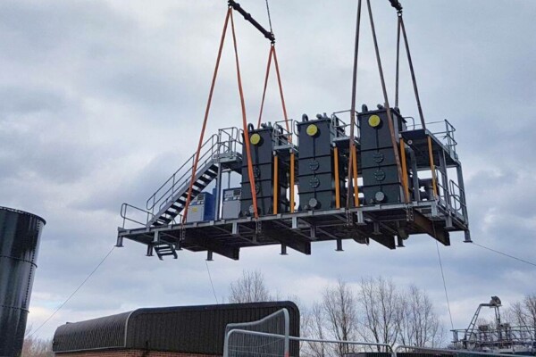 A large piece of heavy machinery is craned into place with a mobile crane using specialist lifting equipment