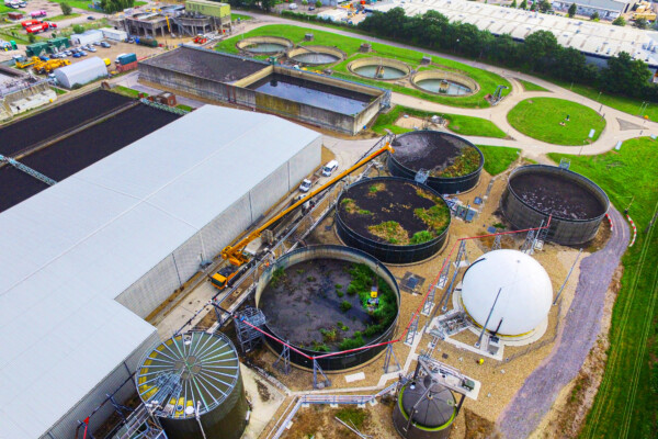 Aerial view of mobile crane using grab attachment to remove material from a water processing plant tank