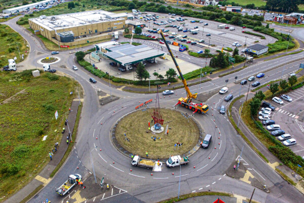 mobile crane at a roundabout lifting sculpture