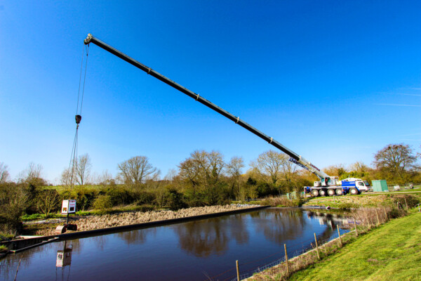 A wide angle view of a mobile crane with a grab working at a water plant