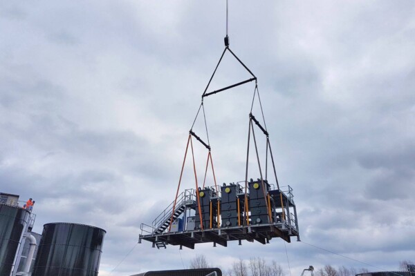 A machine is suspended in the air using specialist lifting equipment with a mobile crane