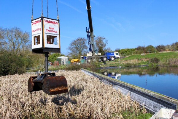 close up of a grab attachment on a mobile crane working to remove material from a water tank
