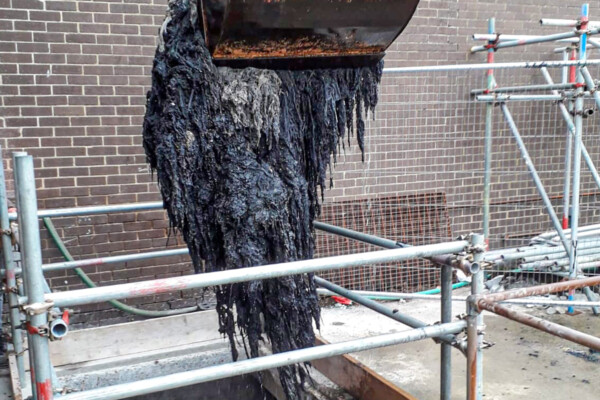 close up of a grab attached to a mobile crane removing wet wipes from a sewage treatment plant