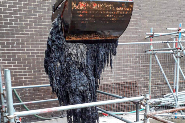 Close up of a grab bucket pulling a collection of flushed wet wipes from a sewage treatment plant