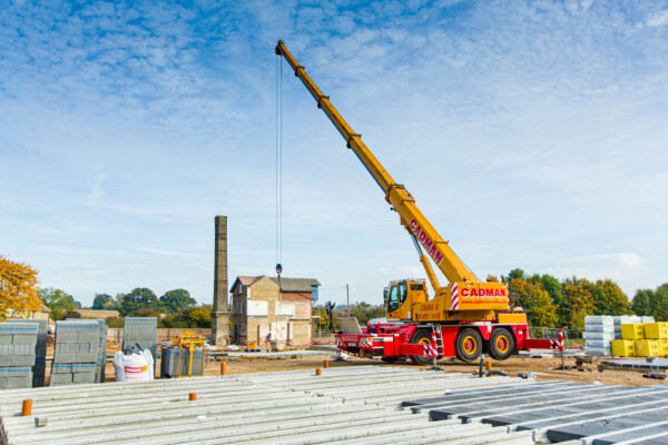 Mobile crane lifts concrete blocks for beam and block flooring on a construction site
