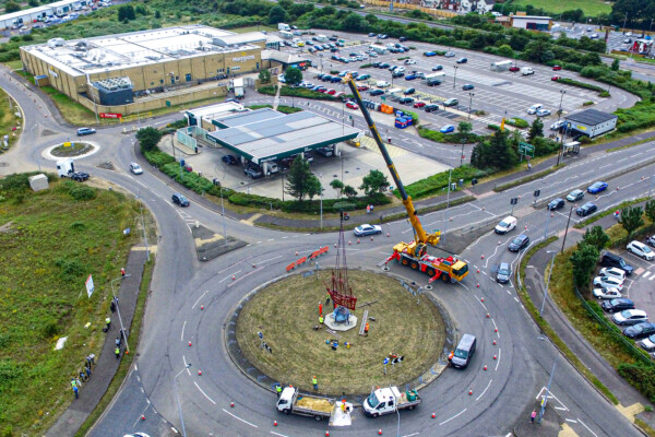 mobile crane at a roundabout lifting sculpture