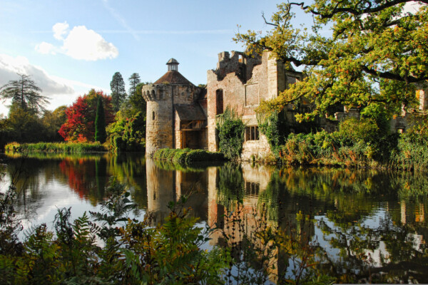 A castle is reflected into a still lake on a summers day in Kent