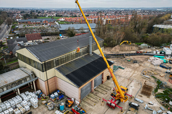 Aerial shot of mobile crane holding worker in man cage to clean gutters