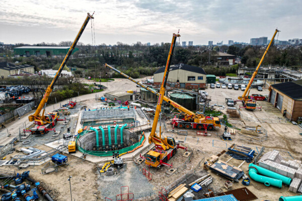 A collection of yellow mobile cranes work at an Anglia Water site installing pipework
