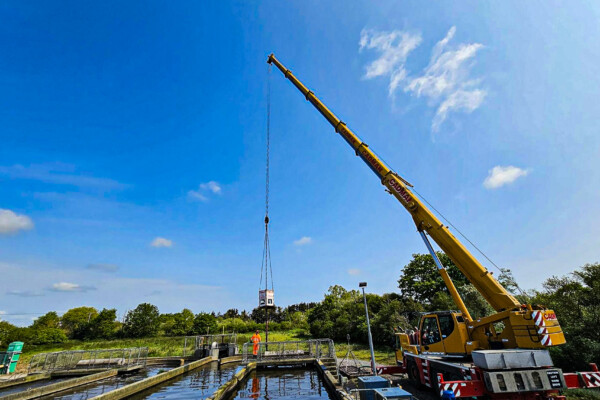 Mobile crane works at a water treatment plant with a grab on hire to remove waste