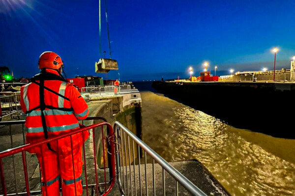 A mobile crane and operator work at night time with a remote controlled grab