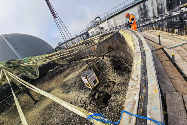 A grab removes a large collection of solidified mud on top of a water tank