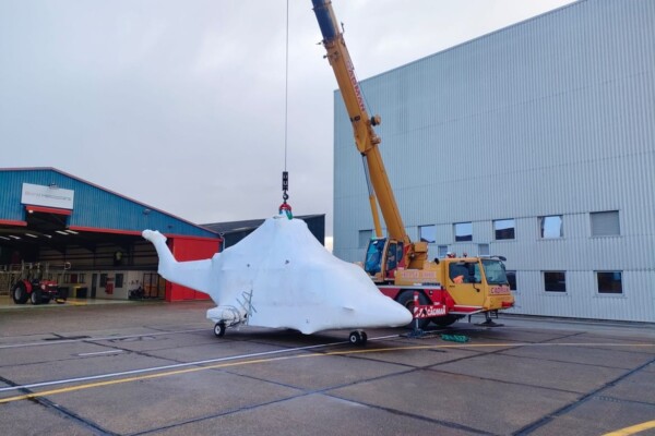 Helicopter wrapped in plastic lifted by mobile crane at Norwich Airport