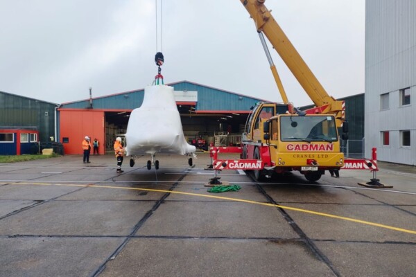 Helicopter is lifted by mobile crane as part of delivery program at Norwich Airport