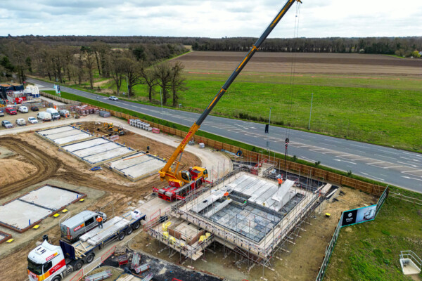 Yellow mobile crane installs concrete hollowcore floors on a new build construction site