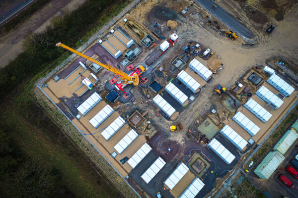 Mobile crane works from BESS battery storage site installing battery units for renewables