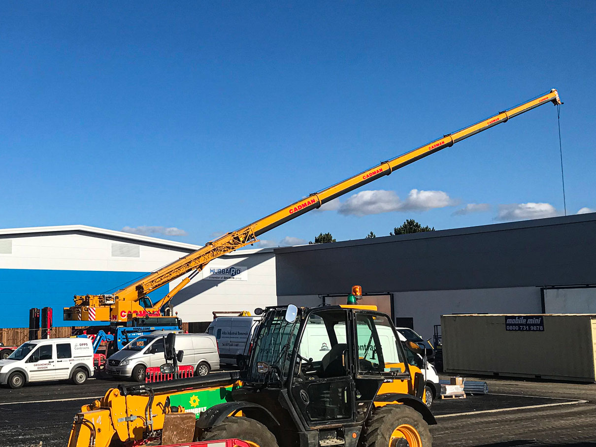 mobile crane with long boom installs air conditioning